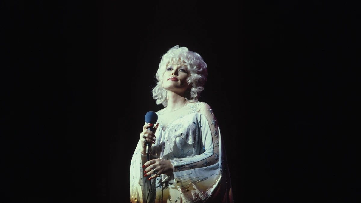 Dolly Parton singing on stage, holding a microphone